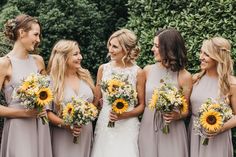 a group of women standing next to each other holding sunflowers and bouquets