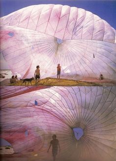 two people standing in front of large white parasols with dogs on the ground