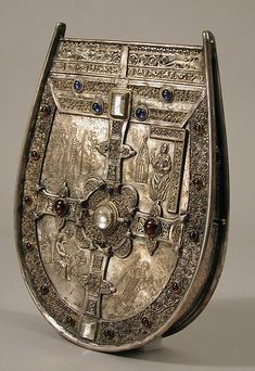 an ornately decorated silver plate with blue and red stones on the front, sitting on a white surface