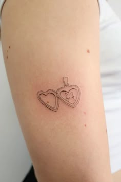 a woman with a tattoo on her arm that has two hearts in the shape of a heart