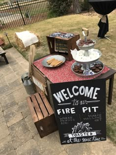 a sign that is sitting on top of a wooden table in the middle of a yard