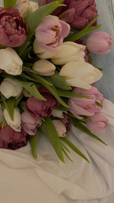 a bouquet of pink and white tulips on a bed