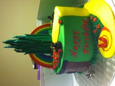 a birthday cake is decorated with green frosting and rainbows on the bottom layer