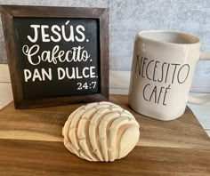 a coffee cup and some cookies on a wooden table next to a chalkboard with the words jesus cafetto pan dulce