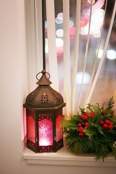 a red lantern sitting on top of a window sill next to a potted plant