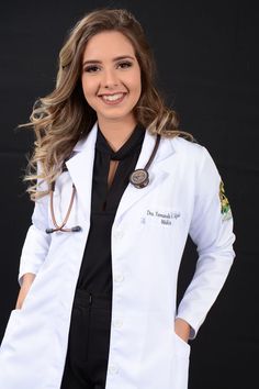 a woman wearing a white lab coat and black shirt standing with her hands on her hips