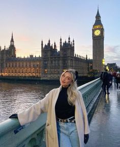 a woman standing on a bridge in front of the big ben clock tower