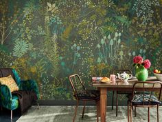 a dining room table with chairs and a green wallpapered in floral designs on it