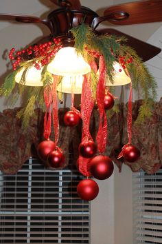 a ceiling fan with christmas decorations hanging from it's blades and two lights on top