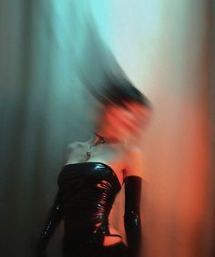 a woman in black latex is standing next to a curtain