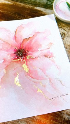 a pink flower painted on white paper next to a paintbrush