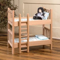 a doll sitting on top of a wooden bunk bed next to a small christmas tree