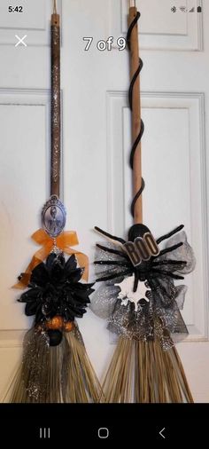 two brooms are hanging on the front door with ribbons and decorations attached to them