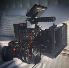 a camera sitting on top of a bed next to a pillow