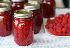 red raspberry jam in glass jars lined up on a table