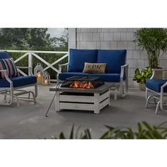 a fire pit sitting on top of a patio next to blue chairs and tables with pillows