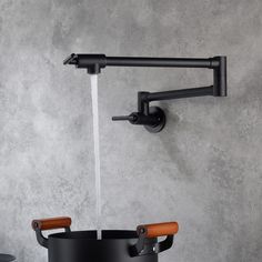 a black faucet with two wooden handles on the wall next to a pot