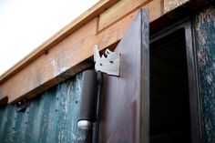 a close up of a metal object on the side of a building near a door