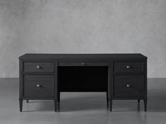 a black desk with two drawers and one drawer on the top, in front of a gray wall