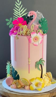 a pink and yellow cake with flamingos, palm trees, and other tropical decorations