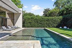 an outdoor swimming pool with lounge chairs next to it and grass in the back yard