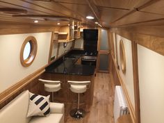 the interior of a boat with wood paneling and black counter tops, white stools, and wooden walls