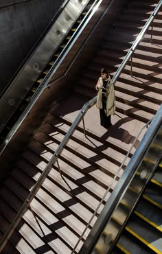 a woman is walking down an escalator with her cell phone