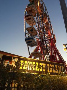 an amusement park with a ferris wheel and many signs on the side of it that read fantasy island