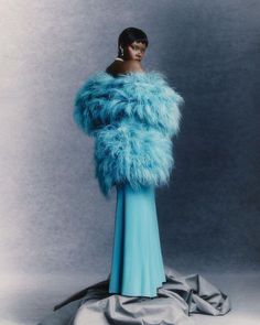 a woman in a blue dress and fur coat