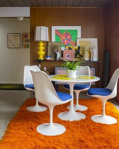 a dining room with an orange rug and white chairs