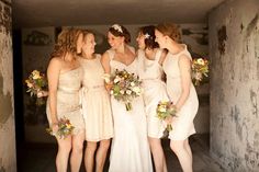 a group of women standing next to each other wearing dresses and holding bouquets in their hands