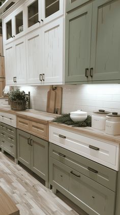 a kitchen with green cabinets and white counter tops, wood flooring in the middle