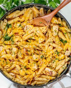 a skillet filled with pasta, chicken and parsley on top of a checkered table cloth