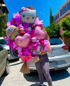 a woman in tights and heels holding up a hello kitty balloon bouquet on the street