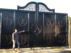 a man standing in front of a black gate with an ornamental design on the side