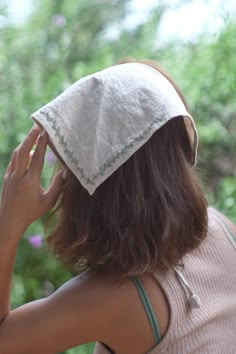 a woman wearing a white hat and holding her hands to her face while looking out the window