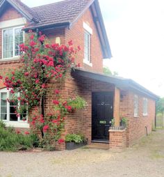 a brick house with red flowers growing on it's side