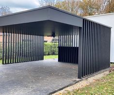 a black metal structure sitting in the middle of a yard next to a white building