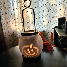 a candle holder with a carved pumpkin on it sitting on a table in front of a curtain