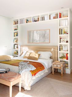 a bedroom with a bed, bookshelves and a bench in the middle of it