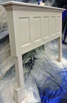 a white bed frame sitting on top of a floor covered in blue and gray paint