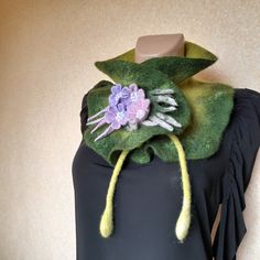 a black dress with green and purple flowers on the front, attached to a mannequin's head