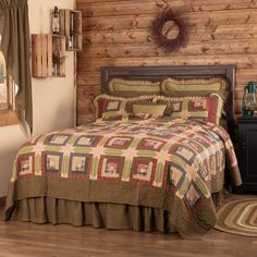 a bed in a room with wooden walls and wood flooring that has a large quilt on it