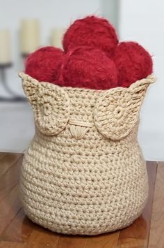 a crocheted basket with balls of yarn in it sitting on a wooden table