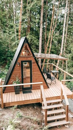 a small cabin in the woods with stairs leading up to it