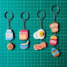 four different kinds of food key chains on a green surface with grids in the background