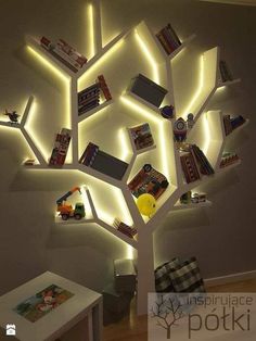 a tree made out of books is lit up with white lights and some pictures on it