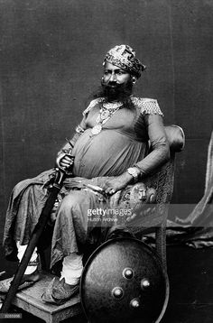 an old photo of a man sitting in a chair with a helmet on his lap