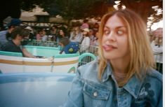 a woman with her mouth open sitting in front of an amusement park filled with people