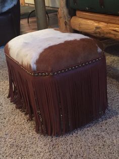 a brown and white ottoman sitting on top of a carpet next to a wooden bench